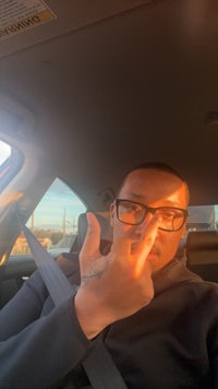 a man in glasses sitting in the back seat of a car